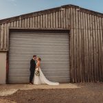 Bride and groom outside rustic barn.