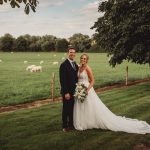 Bride and groom in countryside wedding scene.