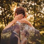 Romantic couple embracing in sunlit forest.