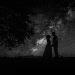 Couple silhouetted under starry night sky