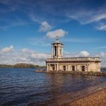 Historic church by Rutland Water under blue sky