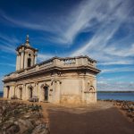 Historic church by a lake under blue sky.