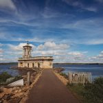 Historic church by Rutland Water, cloudy sky background.