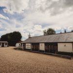 Country cottage with gravel driveway and blue sky.