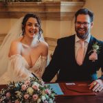 Smiling couple at their wedding ceremony signing registry.