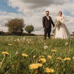 Bride and groom in field with flowers.