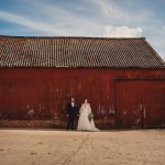 Wedding couple in front of rustic red barn.