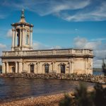 Historic church on Rutland Water under blue sky.