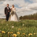 Bride and groom standing in a field of dandelions.