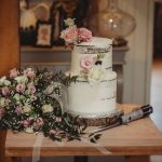 Rustic wedding cake with floral bouquet and lightsaber.