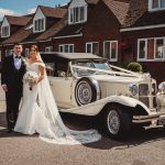 Bride and groom with vintage wedding car