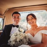 Happy wedding couple in car with bouquet