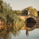 Couple standing on a stone bridge over river.