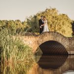 Couple standing on a stone bridge over river.