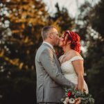 Bride and groom kissing outdoors at sunset.