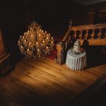 Elegant chandelier above staircase with wedding cake table.