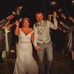 Bride and groom exit with sparklers at night.