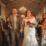 Bride and groom walking down the aisle, smiling.