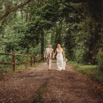 Couple walking down forest path on wedding day.