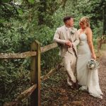 Newlyweds posing on woodland path, summer wedding.