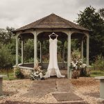 Wedding dress hanging in a garden gazebo.