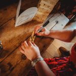 Person signing a wooden guestbook piece.