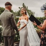 Outdoor wedding ceremony with officiant and couple exchanging vows.