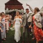 Bride and groom walking through confetti at wedding.