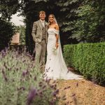 Couple in wedding attire in a garden pathway.