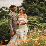 Bride and groom in floral garden, smiling happily.