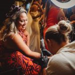 Woman smiling, getting a tattoo at an event.