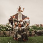 Bride tossed by groomsmen in garden wedding celebration.