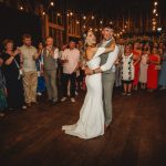 Couple dancing at wedding reception with guests watching.