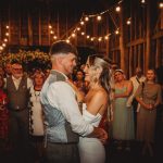 Couple dancing at wedding, surrounded by cheerful guests.