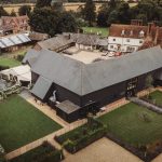 Aerial view of rustic countryside buildings and gardens.