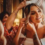 Bride preparing with friends, adjusting veil and earrings.