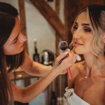 Makeup artist applying lipstick to bride