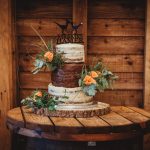 Rustic wedding cake with flowers on wooden table.