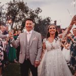 Newlyweds holding sparklers, celebrating with guests.