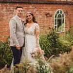 Bride and groom outside brick building, garden setting