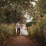 Bride and groom walking in garden path.