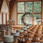 Rustic wedding ceremony setup with floral arch indoors.