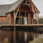 Couple standing on rustic venue balcony over water.