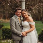 Bride and groom pose in garden during wedding