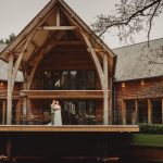 Wedding couple outside rustic wooden venue building.