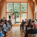 Rustic indoor wedding ceremony with floral decorations.