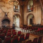 Historic stone room with rows of empty chairs.