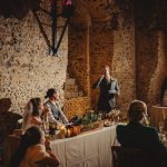 Groom speeches at rustic wedding reception dinner.