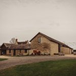 Rustic stone barn with vintage tractor outside.