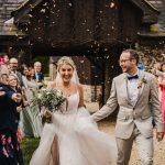 Happy couple walks through wedding confetti celebration.